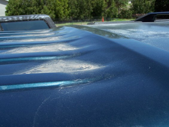 Close-up of a dented, dark blue truck bed cover with visible dust