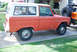 1977 Ford Bronco - A weathered orange and white Ford Bronco is parked on a concrete driveway next to another vehicle.
