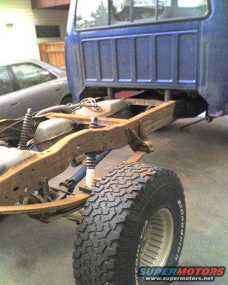 Blue pickup truck chassis with rusty frame and BFGoodrich tire, viewed from rear