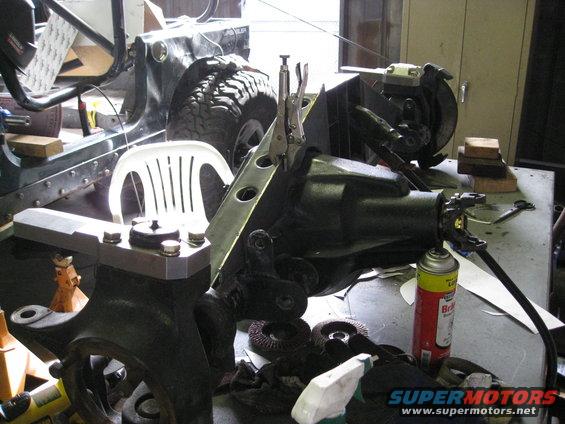 Jeep YJ front axle assembly on a workbench with vice grips and a can of brake cleaner
