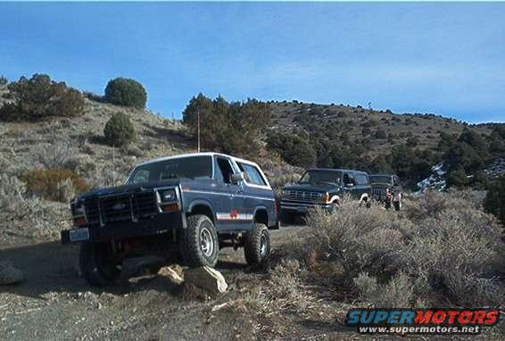 Blue 1980s Ford Bronco and another SUV parked on rocky terrain
