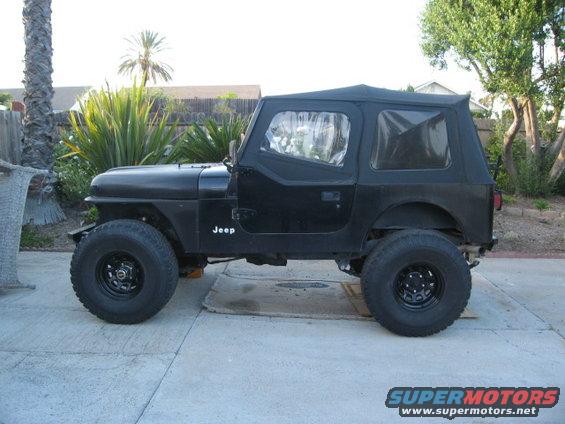 Black Jeep CJ with soft top, side view. Jeep logo visible on fender