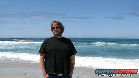 Man in black t-shirt on beach with ocean waves