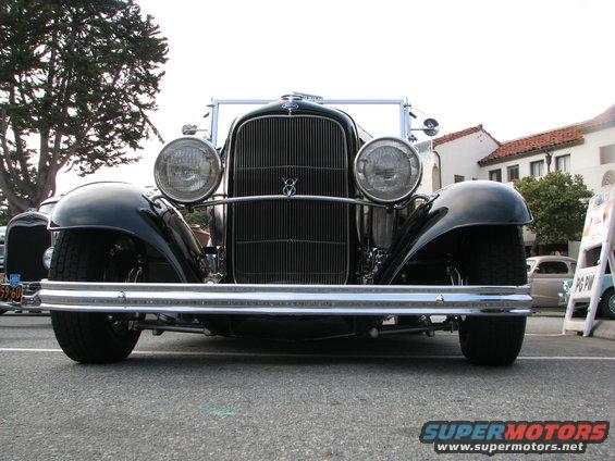 Front view of a black vintage car with a large chrome bumper and vertical grille