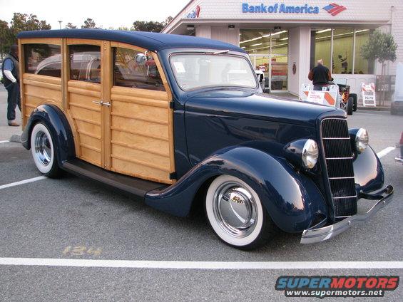 Dark blue 1930s woody wagon with whitewall tires parked in a lot