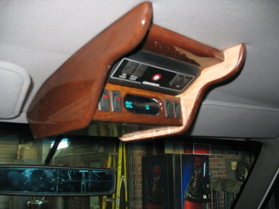 Wood-trimmed overhead console with switches and a green digital display, viewed from inside a vehicle