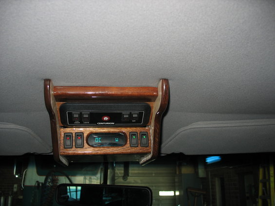 Overhead console with wood trim, a Centurion branded device, and multiple switches