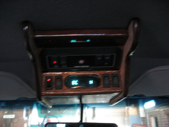 Overhead console with wood trim, digital climate display, and multiple switches