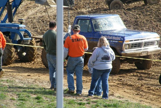 Blue pickup truck with "Smith Pest Control" text on door, people standing nearby, tractor in background