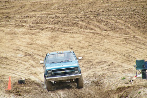 Blue pickup truck driving on a muddy track