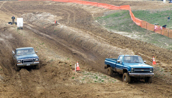 Blue pickup truck navigating a muddy off-road course