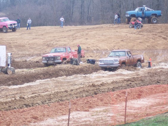 Brown pickup truck stuck in mud, front view. Grille and headlights visible