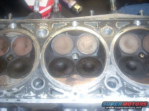 Engine cylinder head with four valves, showing carbon buildup