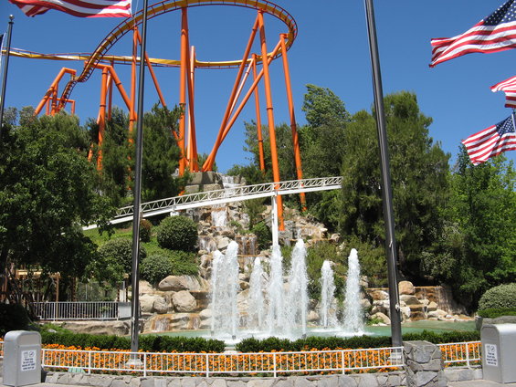 Roller coaster with orange supports above a fountain and landscaping