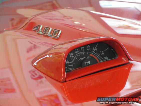 Close-up of a red car's hood with a "400" badge and a tachometer showing "Pontiac RPM"