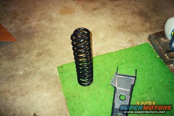 Black coil spring and metal bracket on green mat. Date stamp 3.22.03 and "SUPERMOTORS www.supermotors.net" visible