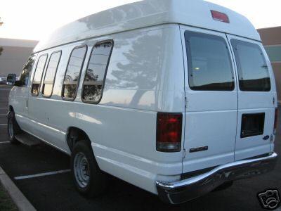 Rear 3/4 view of a white Ford E250 van parked in a lot