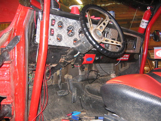 Interior shot of a red vehicle's dashboard and wiring. Looks like a mess of wires