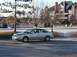 1999 Audi A6 - A silver 1999 Audi A6 sedan is seen from the front-right angle, with a building and trees in the background.