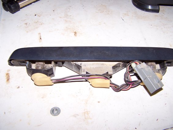 Black automotive light fixture with exposed wiring and a gray electrical connector
