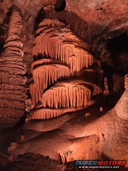 Cave interior with large stalactites and stalagmites illuminated
