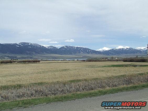 Wide view of a dry grass field with mountains in the background