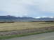 1979 Ford Bronco - A vast field stretches towards snow-capped mountains under a cloudy sky.