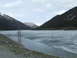 1979 Ford Bronco - A vast, icy lake is surrounded by dark, forested mountains under a cloudy sky.