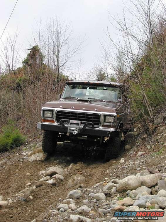Brown 1978 Ford Bronco with winch on front bumper driving on rocky, dirt trail