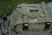 1991 Ford Bronco - A camouflage backpack with multiple straps and buckles is shown outdoors on a paved surface with grass in the background.