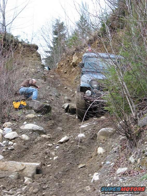 1995 Jeep Wrangler navigating a challenging off-road trail with a person observing