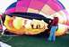 1995 Ford Bronco - A hot air balloon is being laid out on the grass, with people inside and a woman holding ropes.