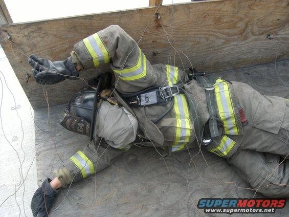 Firefighter in turnout gear lying on the ground, entangled in wires
