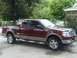 2005 Ford F-150 - A maroon Ford F-150 pickup truck is parked on a driveway in front of a house.