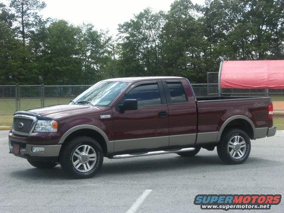 Maroon and tan Ford F-150 truck, driver side view, parked on asphalt