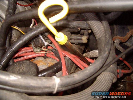 Engine bay with red spark plug wires and a yellow oil dipstick