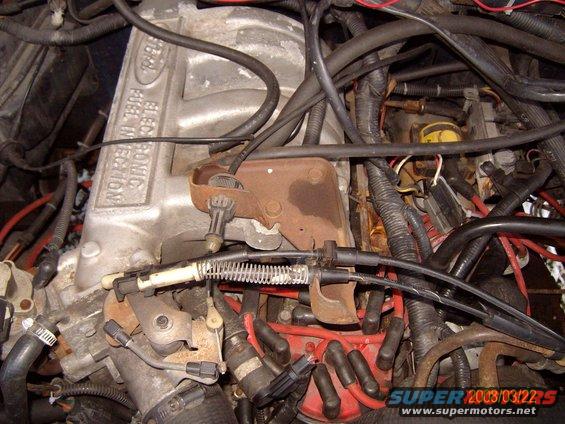 Engine intake manifold with "FORD ELECTRONIC FUEL INJECTION" text, distributor cap, spark plug wires, and throttle linkage