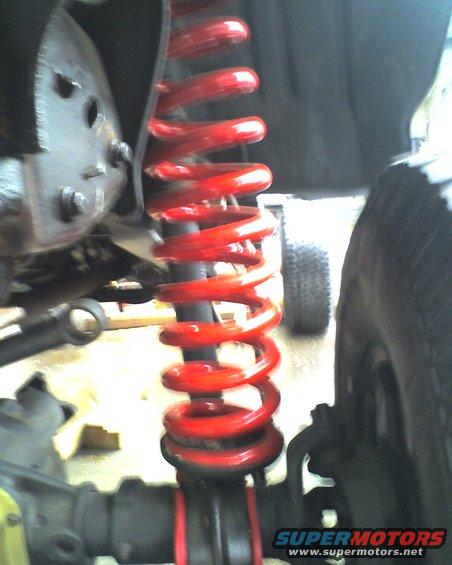 Close-up of a red coilover shock absorber on a vehicle's suspension