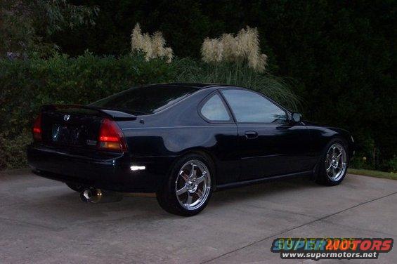 Black coupe with aftermarket wheels parked on concrete