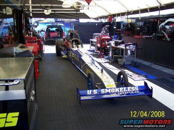 dragster with U.S. Smokeless Tobacco Co. livery in a pit area, with a black SUV in the background