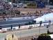 1973 Ford Mustang - A drag car performs a burnout at a race track, generating a large cloud of smoke.