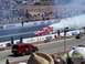 1973 Ford Mustang - A dragster creates a large cloud of smoke during a burnout at a race event.