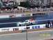 1973 Ford Mustang - A drag racing car speeds down the track, kicking up smoke from its tires.