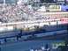 1973 Ford Mustang - Drag racing cars compete on a track with a large crowd in the stands.