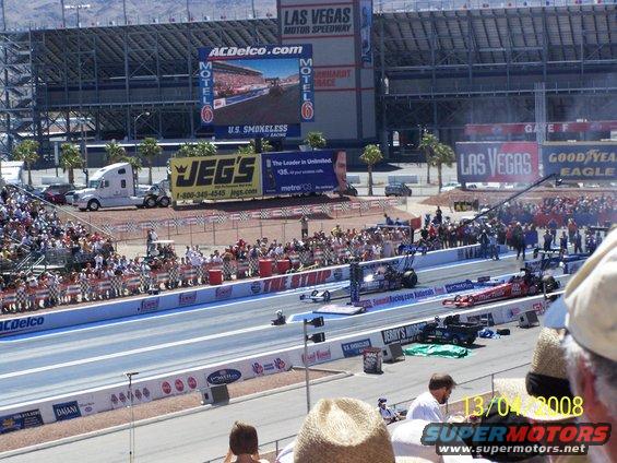 Drag cars lined up at Las Vegas Motor Speedway, crowd watching from stands