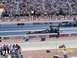1973 Ford Mustang - Two drag racing cars compete on a track, with a crowd watching from the grandstands.