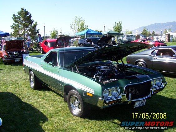 Green 1972 Ford Ranchero with white side stripe, hood open, parked on grass