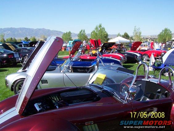 Maroon Shelby Cobra with hood open, parked at a car show