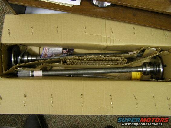 Two metal driveshafts in a cardboard box.