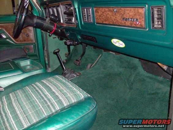 Green interior of a 1978 Ford Bronco with plaid seat inserts and wood grain trim on the dash